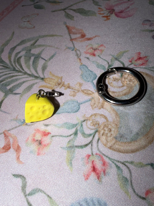 Yellow cheese slice with holes and lobster clasp detached from larger o ring attachment