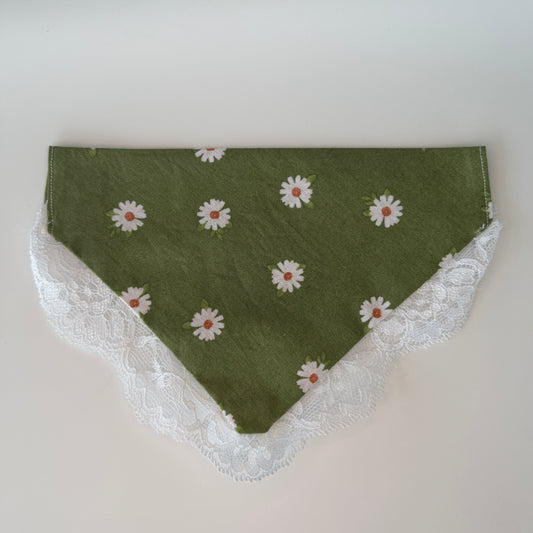 Green dog bandana with white daisy pattern and lace trim on a light gray background