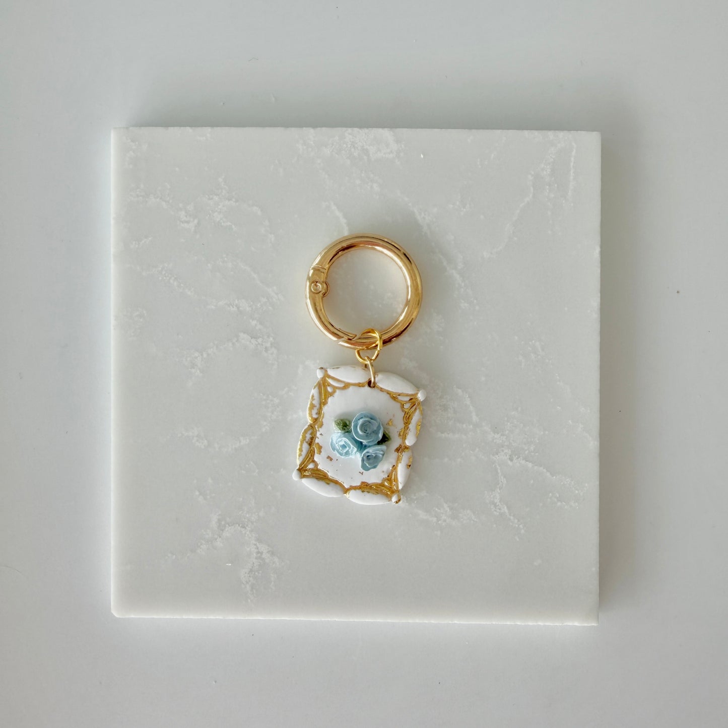 Dog tag with blue and gold floral design on a white marble surface