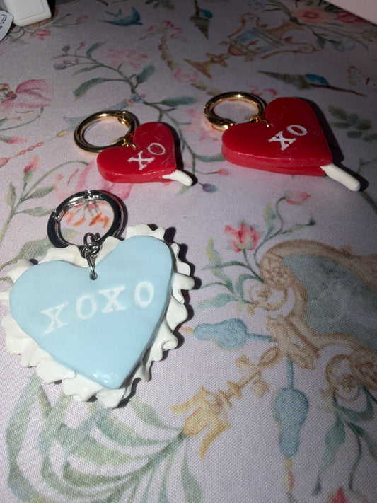 Heart-shaped charms with 'XOXO' text on a floral fabric background