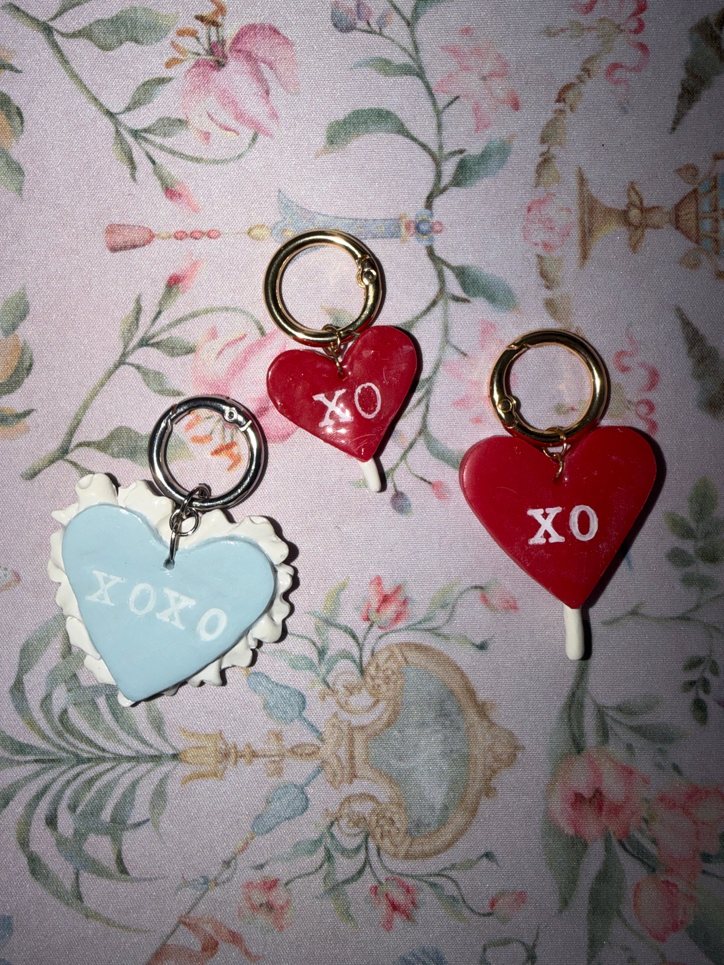 Heart-shaped charms with 'XO' on a floral patterned background