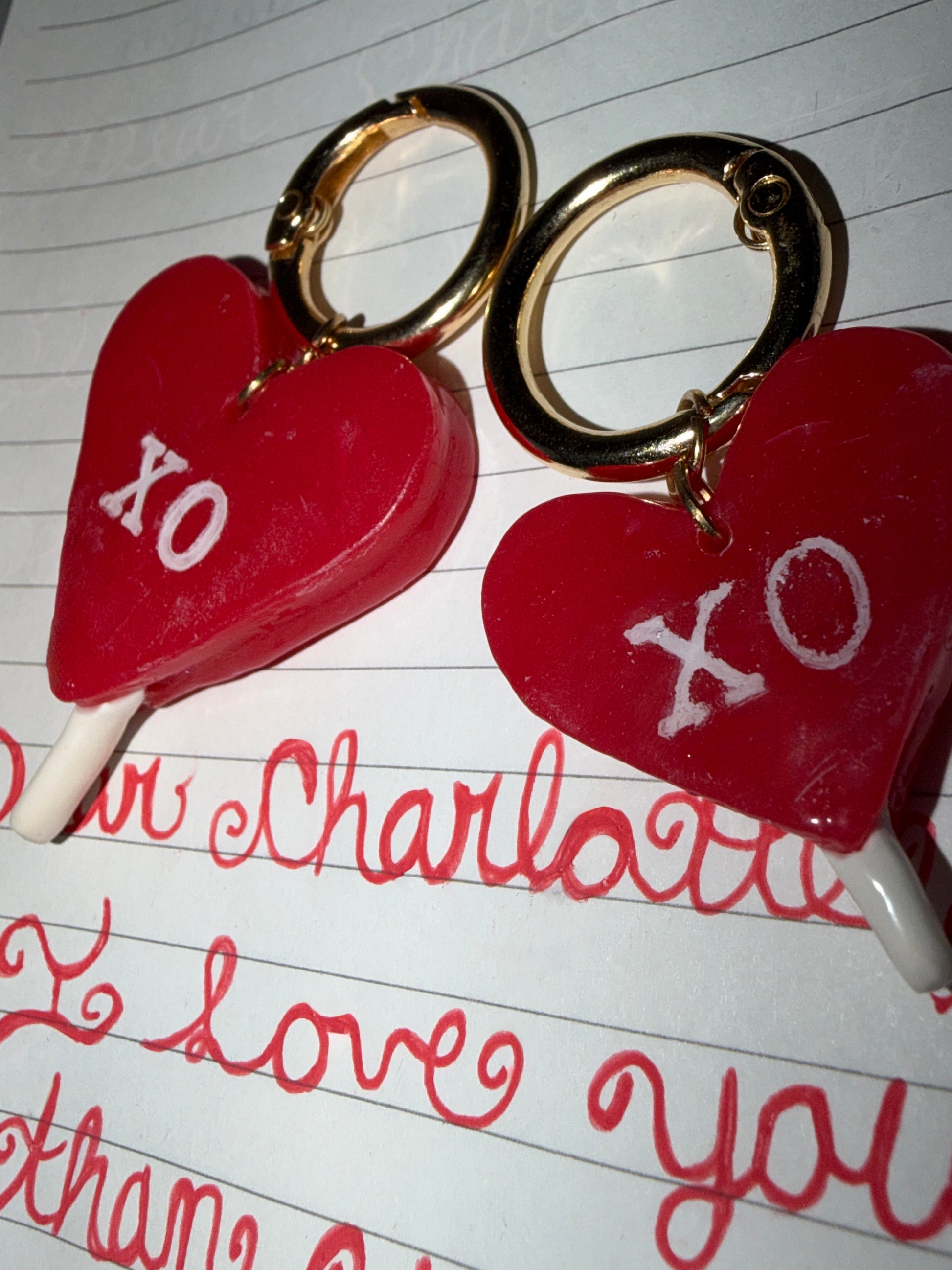 Heart-shaped lollipop pet id tags with 'XO' lettering sitting on a love letter.