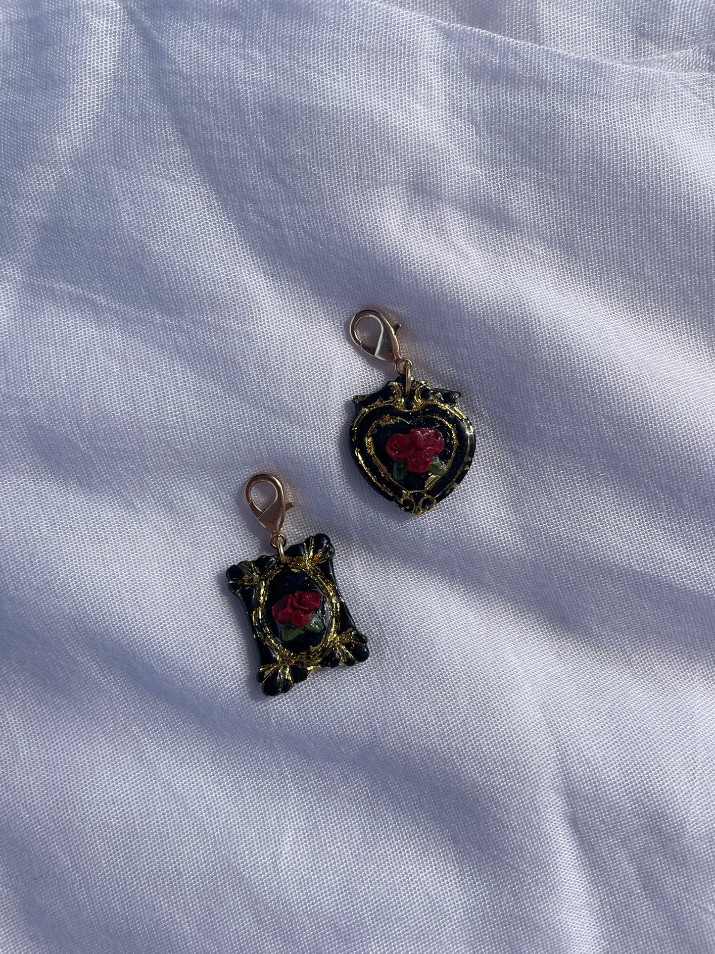 Decorative black pet ID tags with red 3D roses and gold leaf detail pictured on a light fabric background