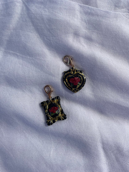 Decorative black pet ID tags with red 3D roses and gold leaf detail pictured on a light fabric background