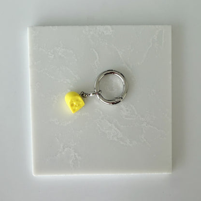 Yellow cheese slice with holes and lobster clasp attached to larger o ring 
