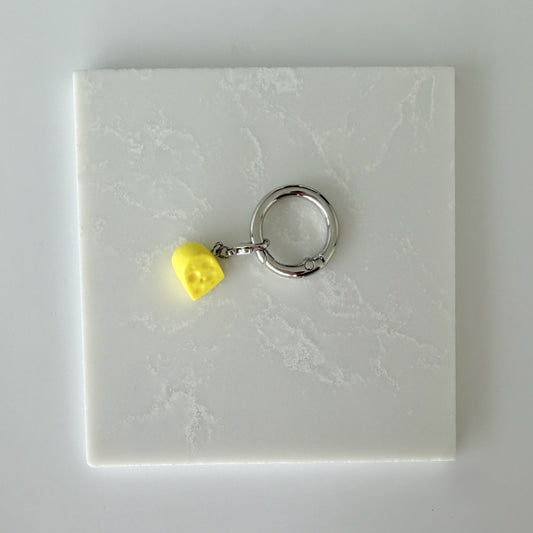 Yellow cheese slice with holes and lobster clasp attached to larger o ring 