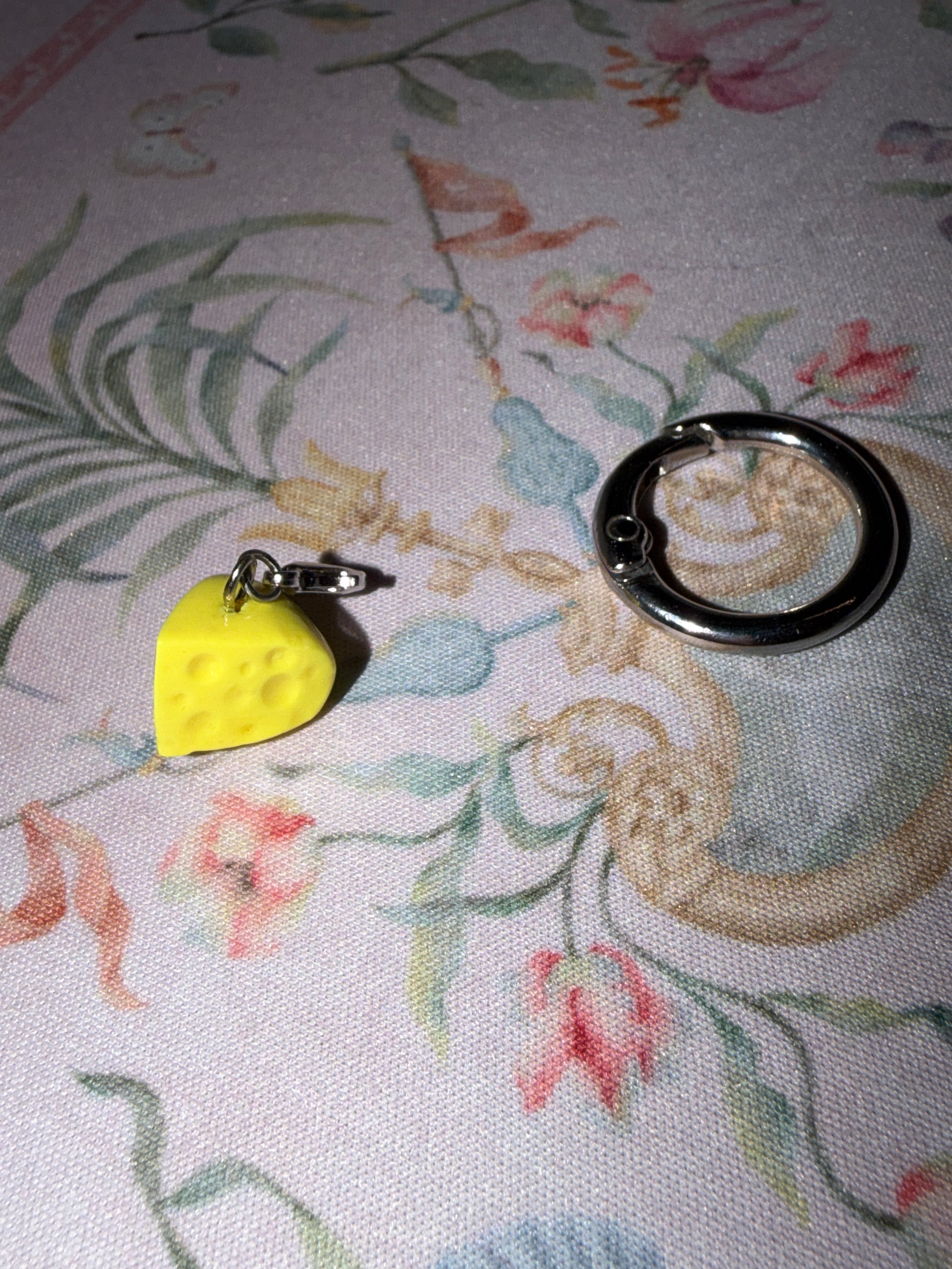 Yellow cheese slice with holes and lobster clasp detached from larger o ring attachment