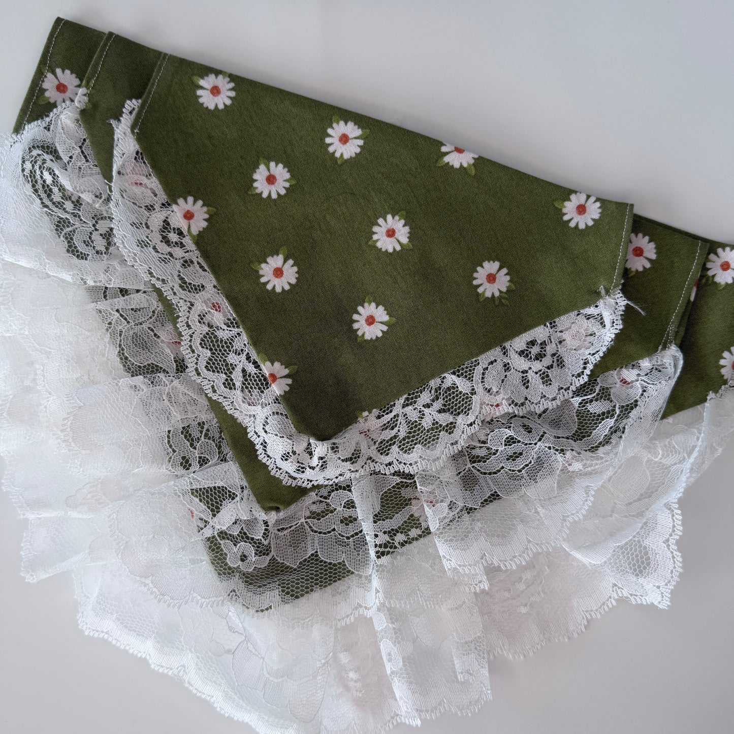 Green cotton over the collar bandanas with white floral patterns and lace trim on a light gray background