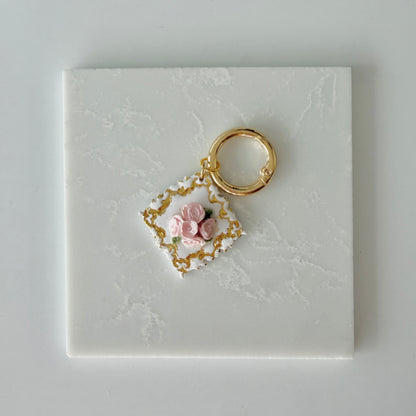 Large Diamond shape pet id tag with 5 pink roses, 4 green leaves, and gold engraving on a white marble background.