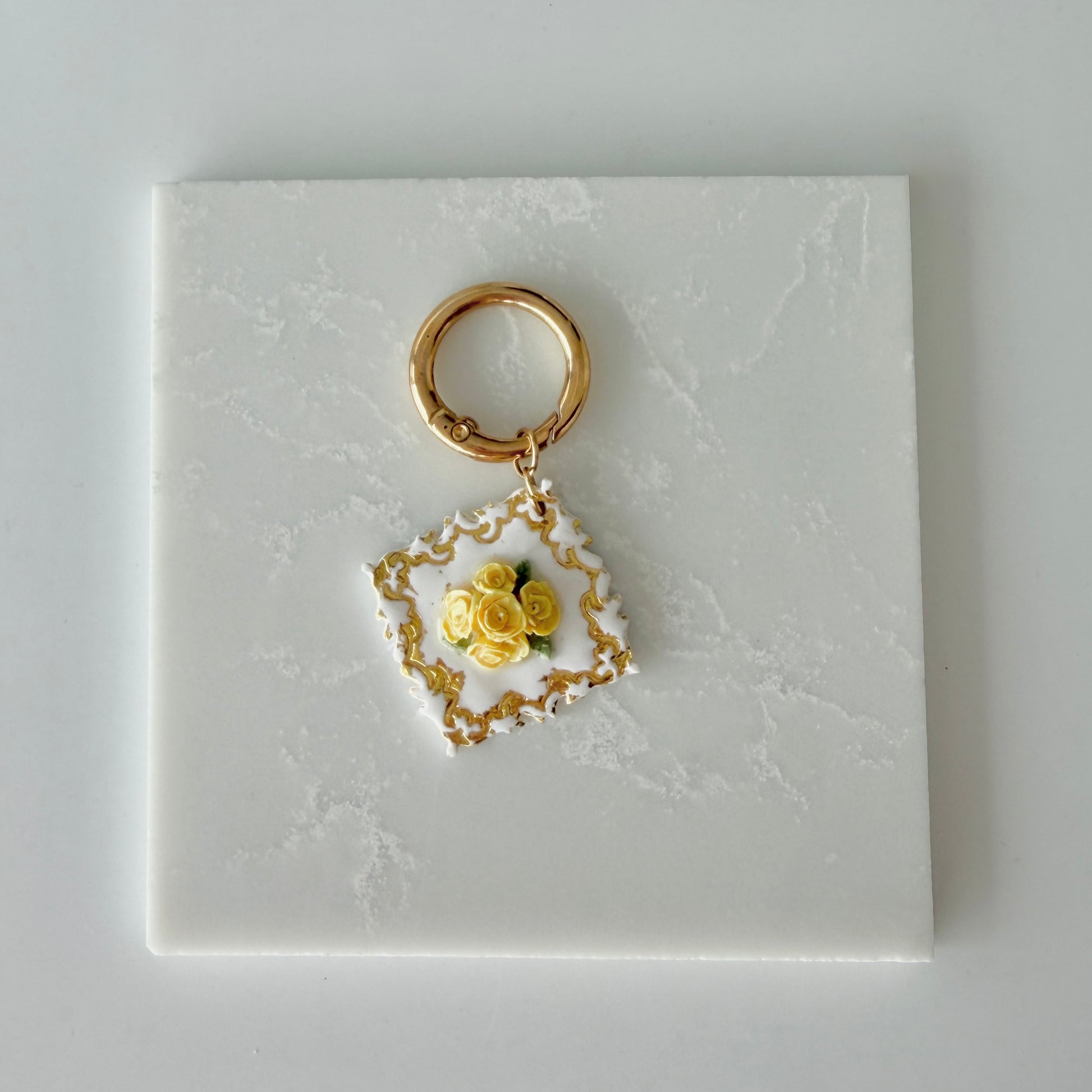 Large Diamond shape pet id tag with 5 yellow roses, 4 green leaves, and gold engraving on a white marble background.
