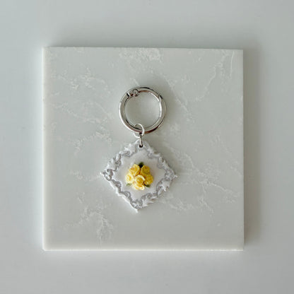 Large Diamond shape pet id tag with 5 yellow roses, 4 green leaves, and silver engraving on a white marble background.