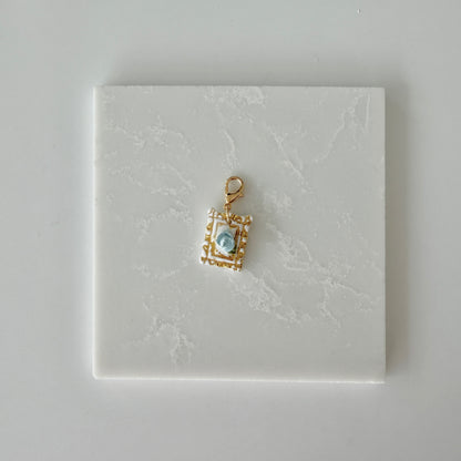 Small pet tag with gold engraving and single blue rose on a white marble background