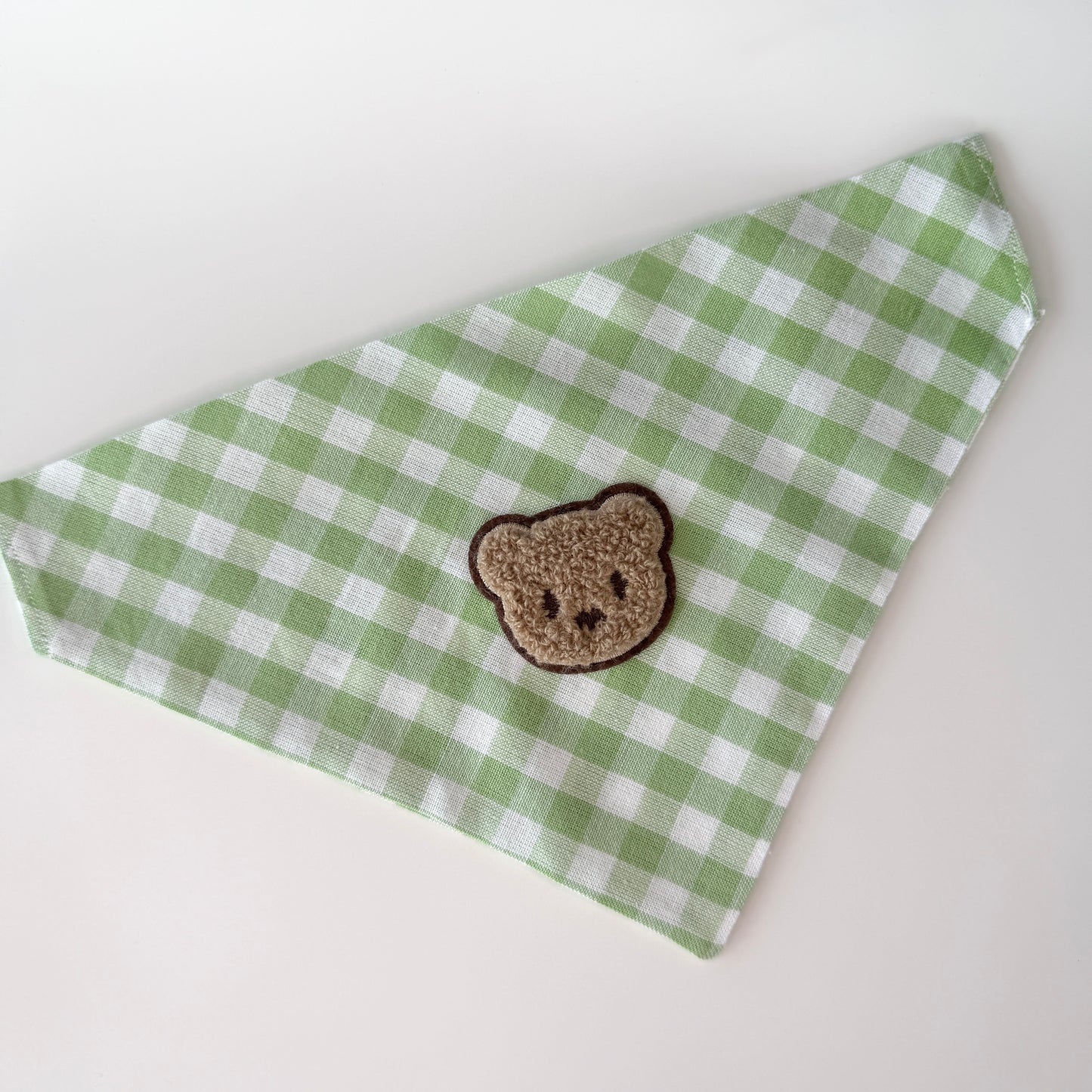Green and white checkered bandana with a brown teddy bear patch on a white background