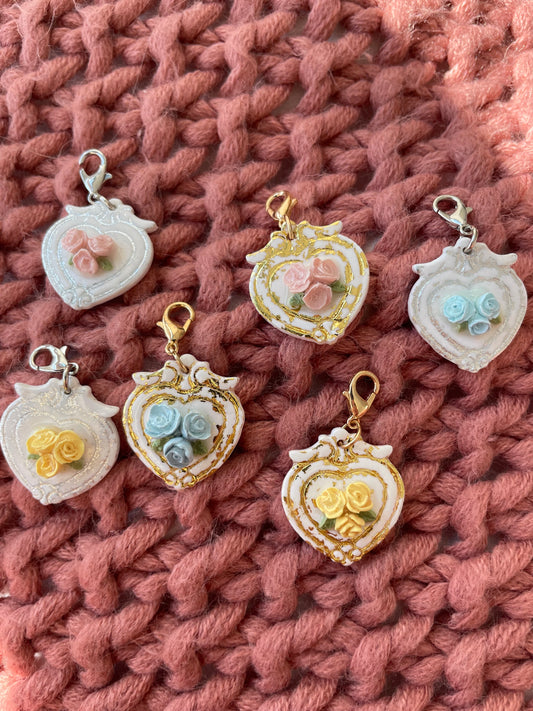 Decorative heart-shaped charms with floral designs on a pink textured fabric background