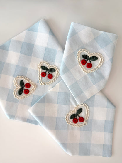 Three blue and white checkered bandanas with embroidered heart designs featuring cherries on a white background.