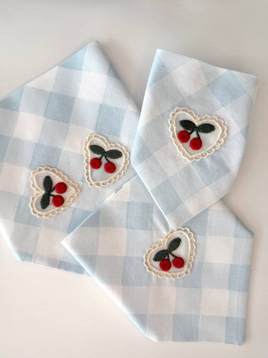 Three blue and white checkered bandanas with embroidered heart designs featuring cherries on a white background.