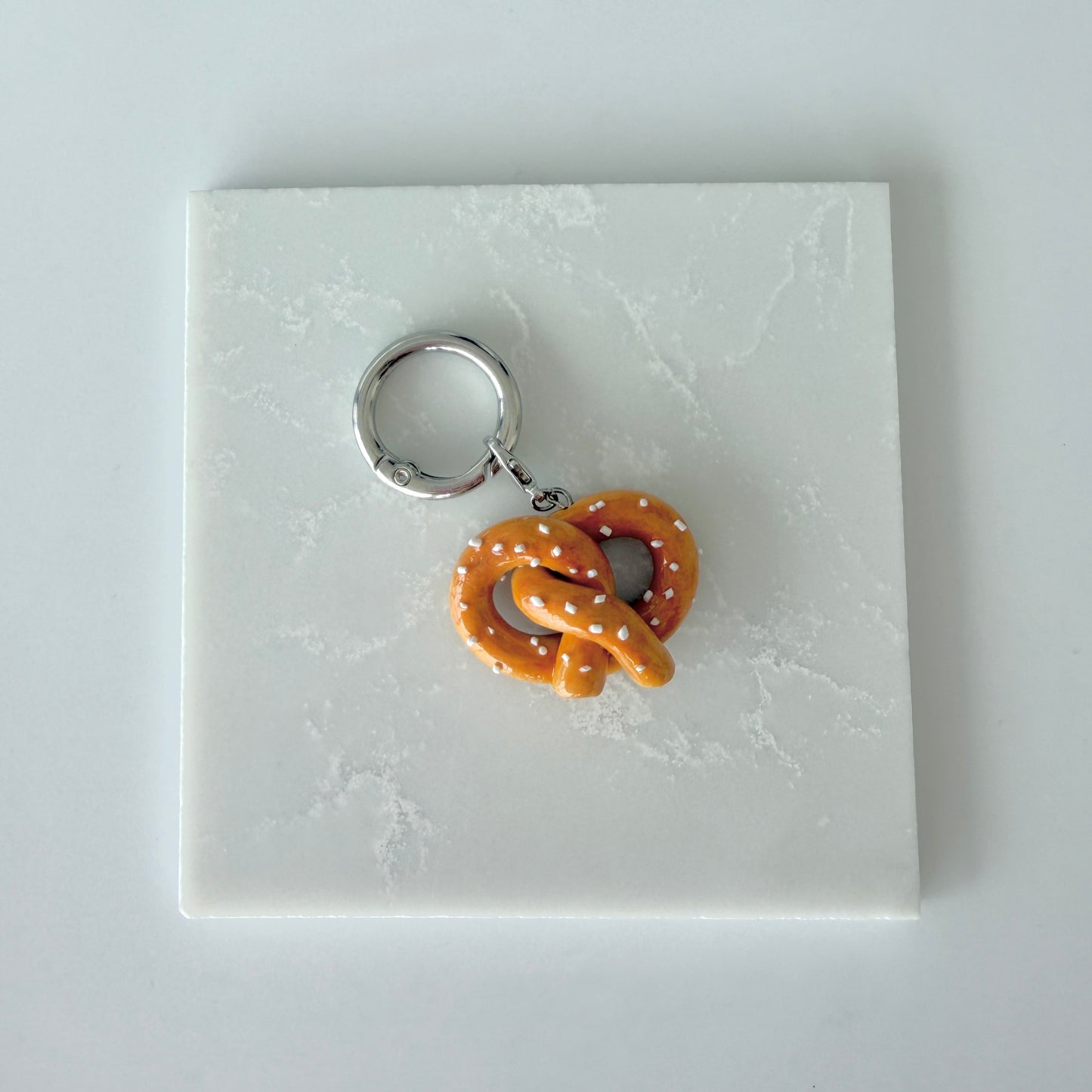 Pretzel-shaped polymer clay charm on a white marble surface