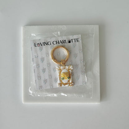 Rectangle pet id tag with 3 yellow roses and gold gilding on a 'Loving Charlotte' branded card in clear packaging.