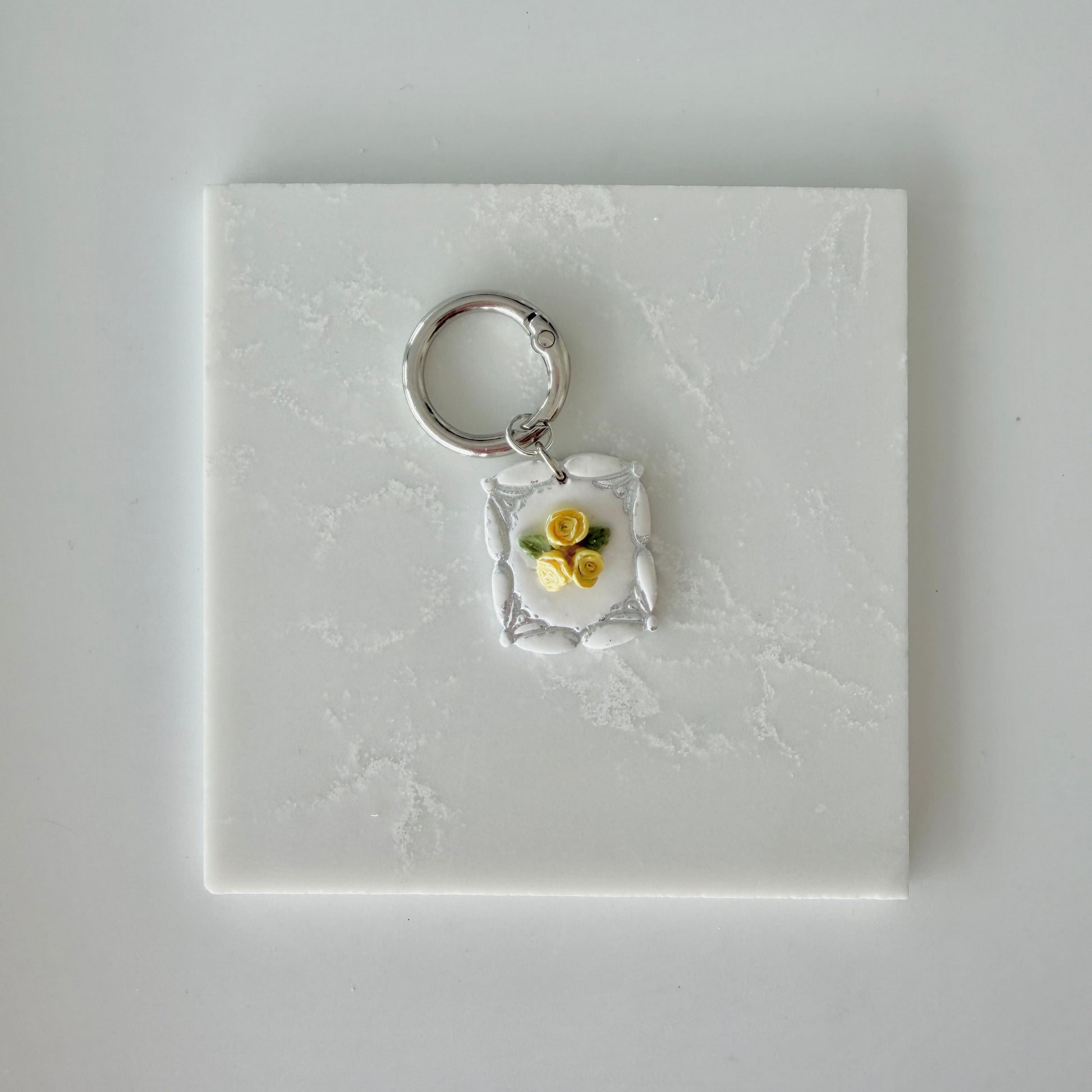Dog tag with yellow and silver floral design on a white marble surface