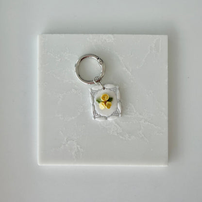 Dog tag with yellow and silver floral design on a white marble surface
